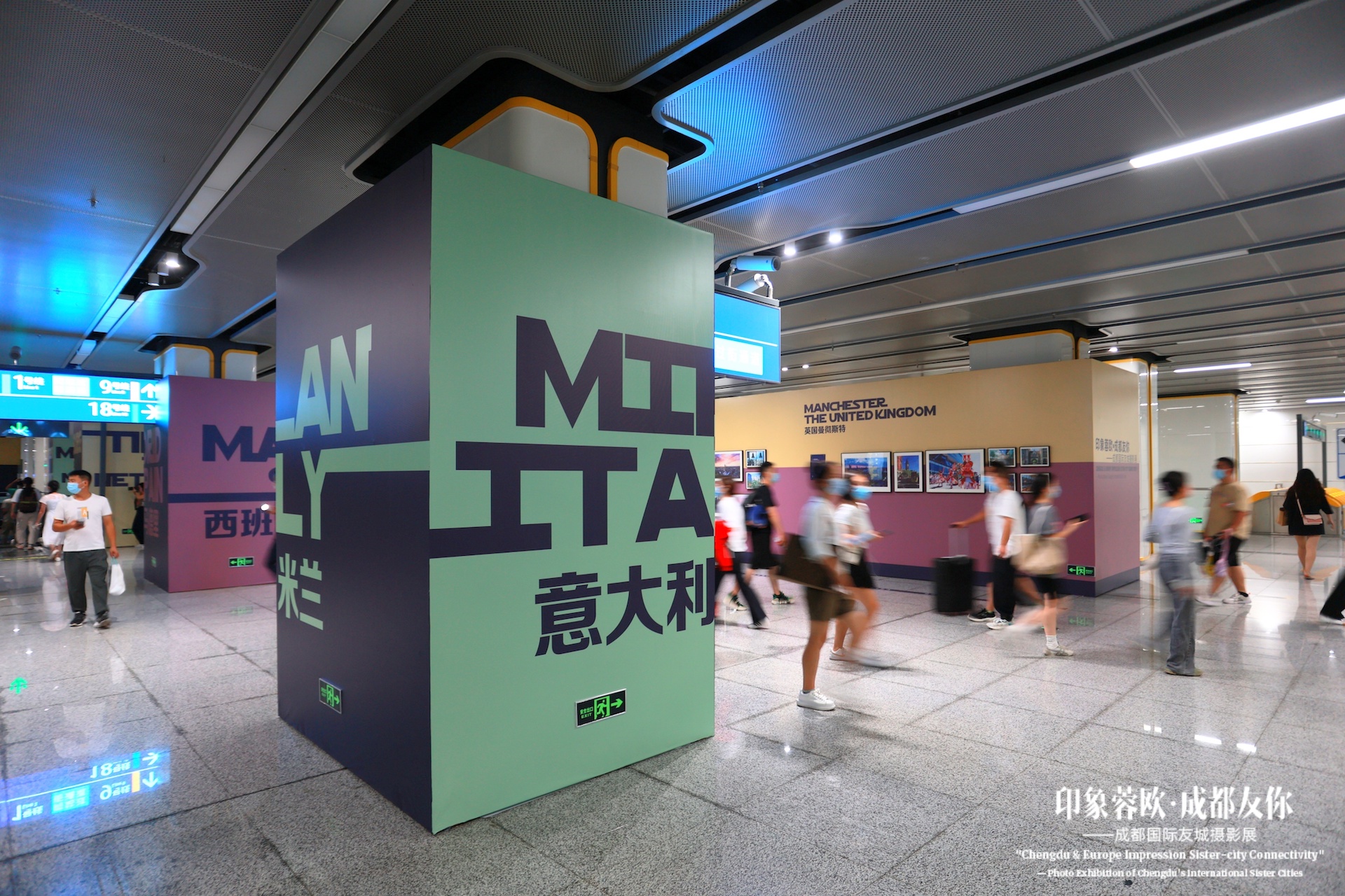 Totem con la scritta 'MILAN ITALY 米兰' nella metropolitana di Chengdu, visitatori in movimento sullo sfondo.