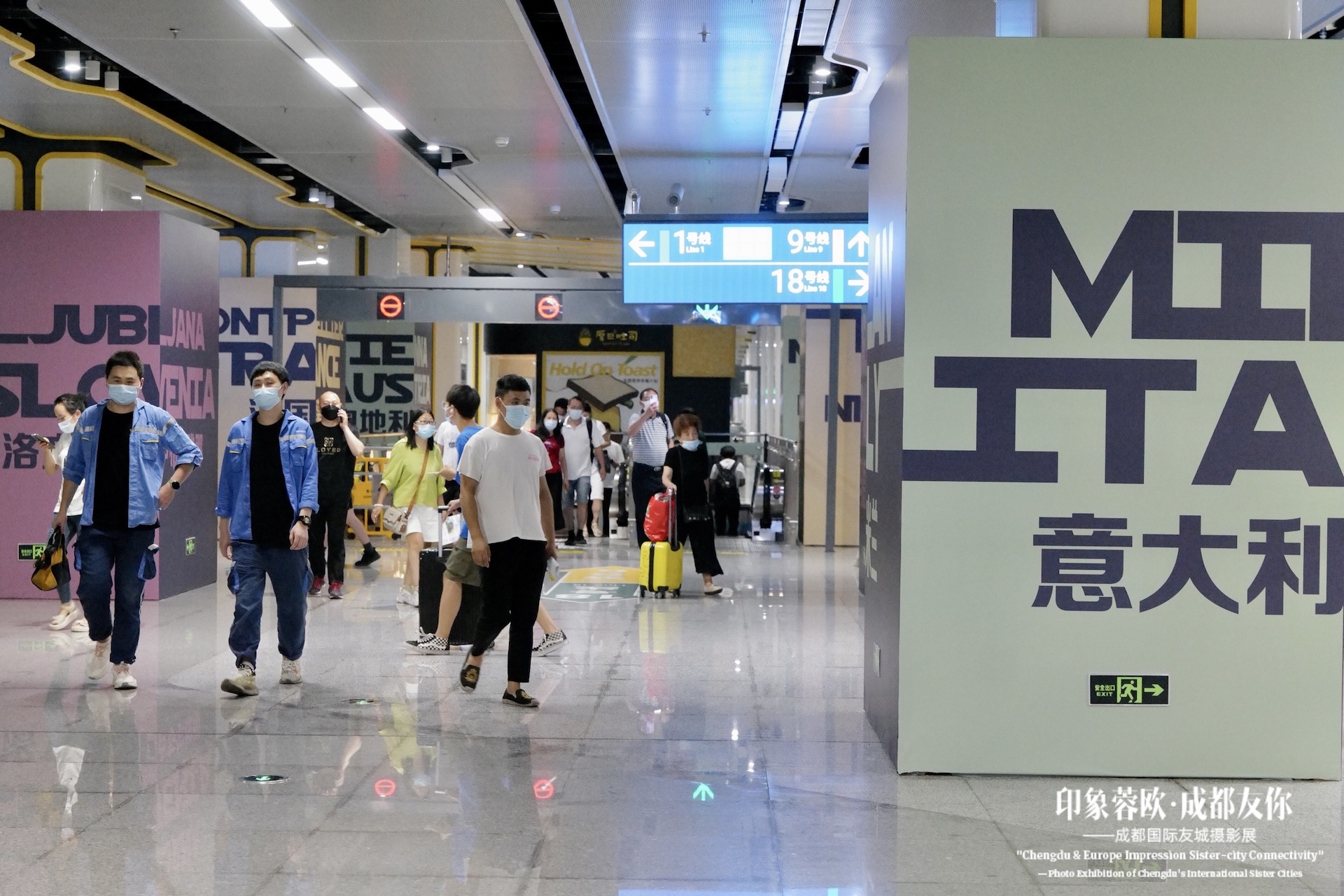 Visitatori che camminano davanti al totem 'MI ITA' della mostra a Chengdu.