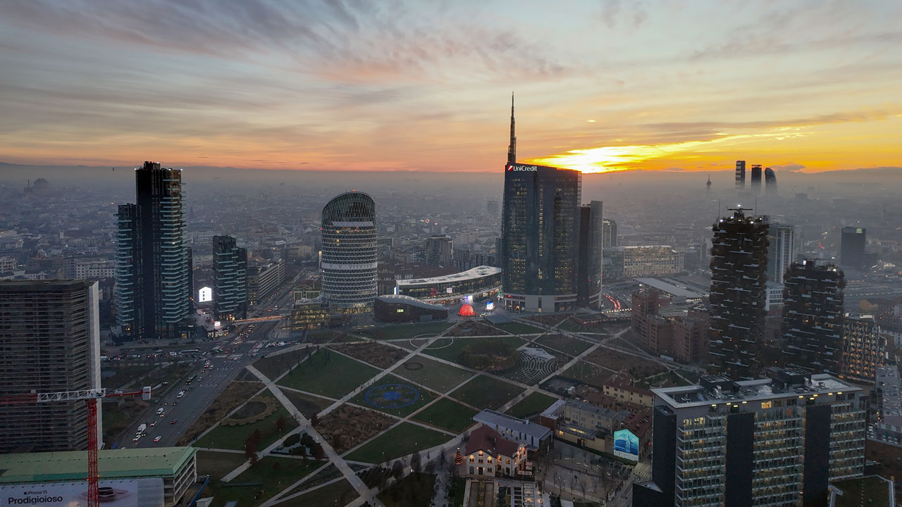 La terrazza panoramica con l'insegna Regione Lombardia, sotto un cielo rosa acceso al tramonto.