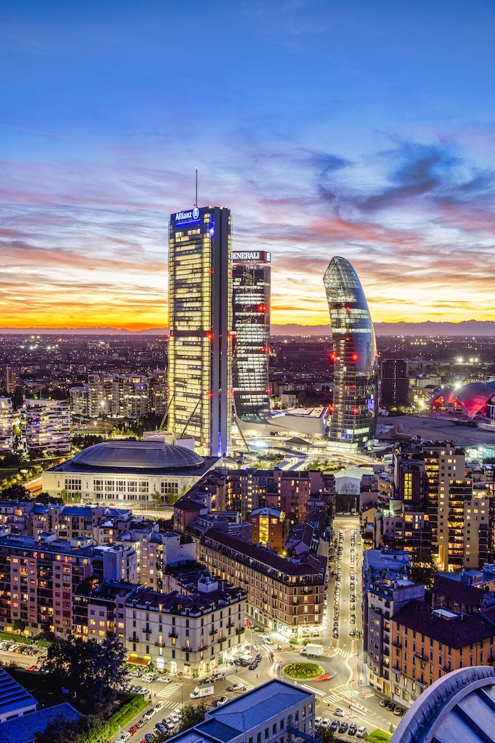 Le Tre Torri di CityLife al tramonto — Allianz, Generali e PwC — con le Alpi all'orizzonte.