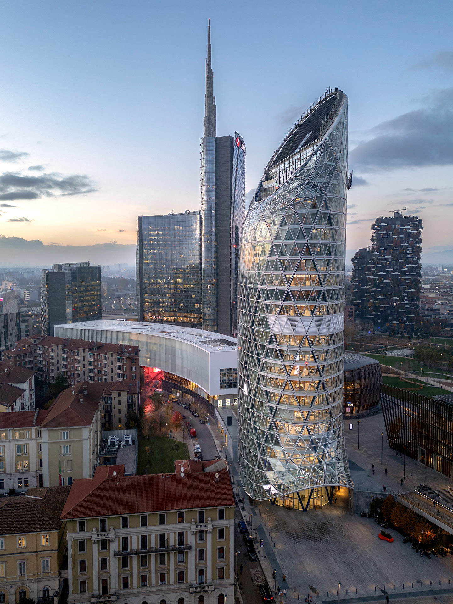 Ripresa ravvicinata della Torre Unipol con la Torre Unicredit e il Bosco Verticale sullo sfondo al crepuscolo.