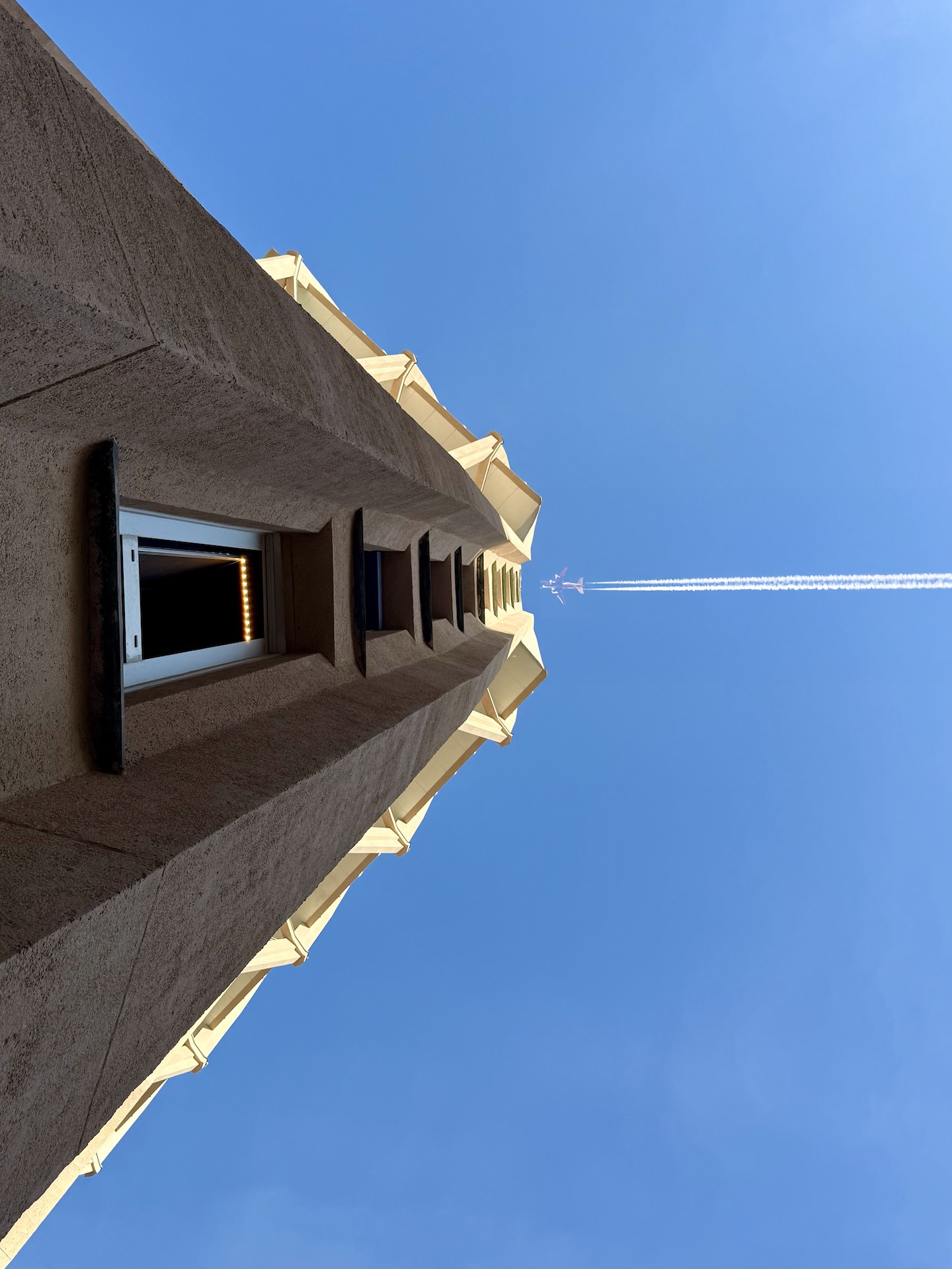 Un aereo acrobatico attraversa il cielo sopra la Torre Velasca, con la scia di condensazione visibile.